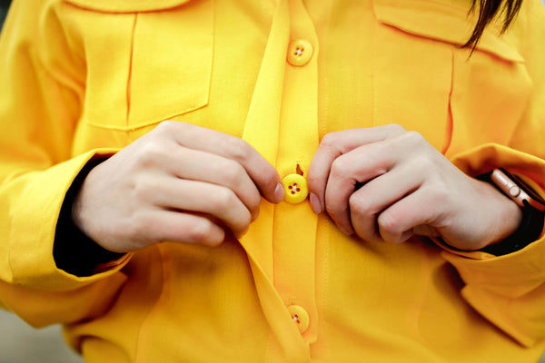 Closeup buttoning a wildland firefighting uniform shirt